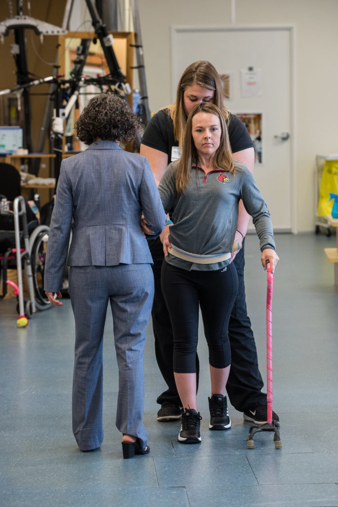 Claudia Angeli and Katie Pfost assist Kelly Thomas use a walker in the KSCIRC lab in Frazier Rehab Institute. 