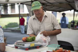 A vendor weighs produce at the Gray Street Farmers Market.