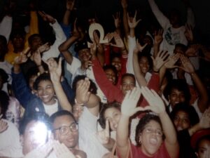 Photo of a group of Black Greek students holding up signs and hand gestures.