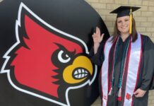Marine Corps Veteran and mom of three keeps a promise to herself as a UofL graduate Christel Blocker stands in front of a Cardinal head in her cap and gown.