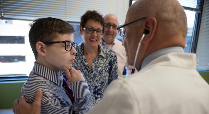 Salvatore Bertolone Jr., M.D., talks with 16-year-old patient Noah Barone during a recent clinic visit as parents Michael and Geneva Barone look on.