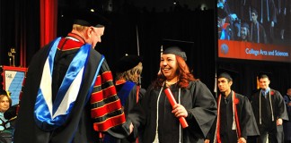 A graduate shakes hands with President James Ramsey at the 2014 December commencement ceremony.