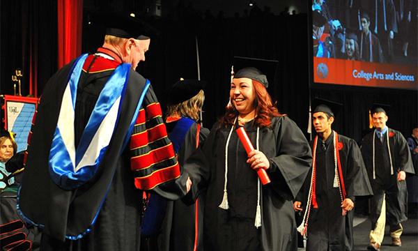 A graduate shakes hands with President James Ramsey at the 2014 December commencement ceremony.