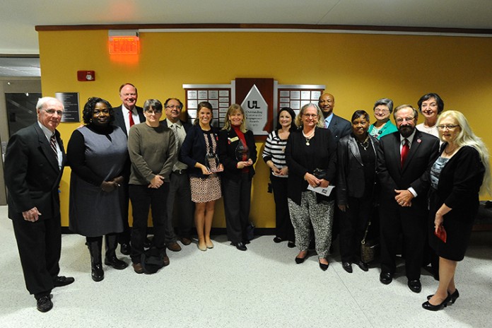 Winners of the 2014 Outstanding Community Engagement Awards surround the plaque in the lower level of Ekstrom Library that bears the names of the winners. Photo by Tom Fougerousse.