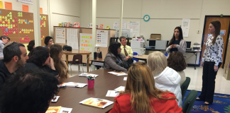 UofL student teachers (standing left to right) Micaela Wang and Brittany Bennison share information about UofL’s CEHD teacher education program and answer questions during the April 12 visit by teachers from Israel.