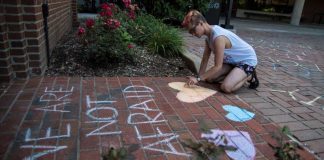 UofL student Kaleb Fischbach draws messages of support outside of the LGBT Center.