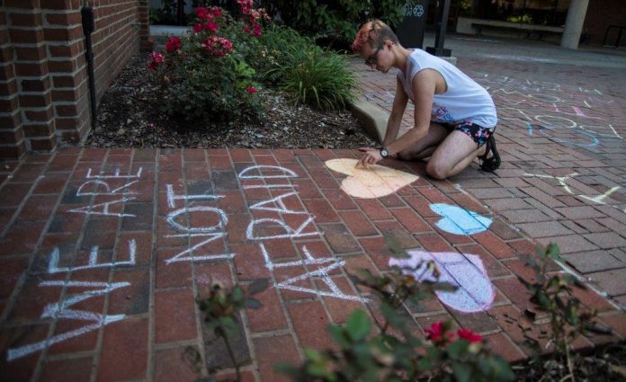UofL student Kaleb Fischbach draws messages of support outside of the LGBT Center.