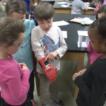 Lucas Abraham, who was born without fingers on his right hand, shows classmates his 'robo-hand.'