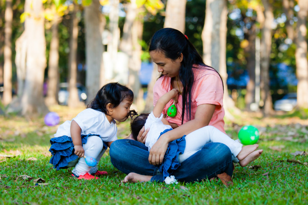 Young mother feeding her baby in the park.