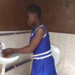 School girl washes hands in new restroom in Ghana.