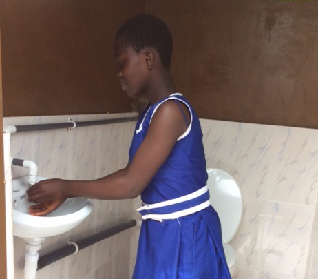 School girl washes hands in new restroom in Ghana.