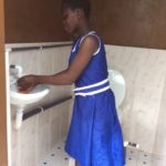 School girl washes hands in new rest-room in Ghana.