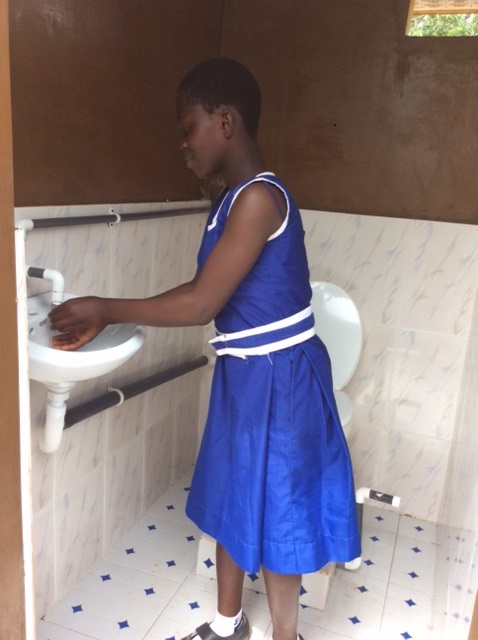 School girl washes hands in new rest-room in Ghana.