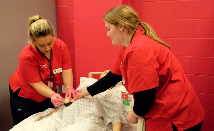 Nursing students in simulation lab. UofL School of Nursing students Abigail Babbitt, left, and Courtney Albers practice administering medications on a patient simulation mannequin in the lab that will be renovated courtesy of $250,000 in donations from The Bufford Family Foundation and Trilogy Health Services.