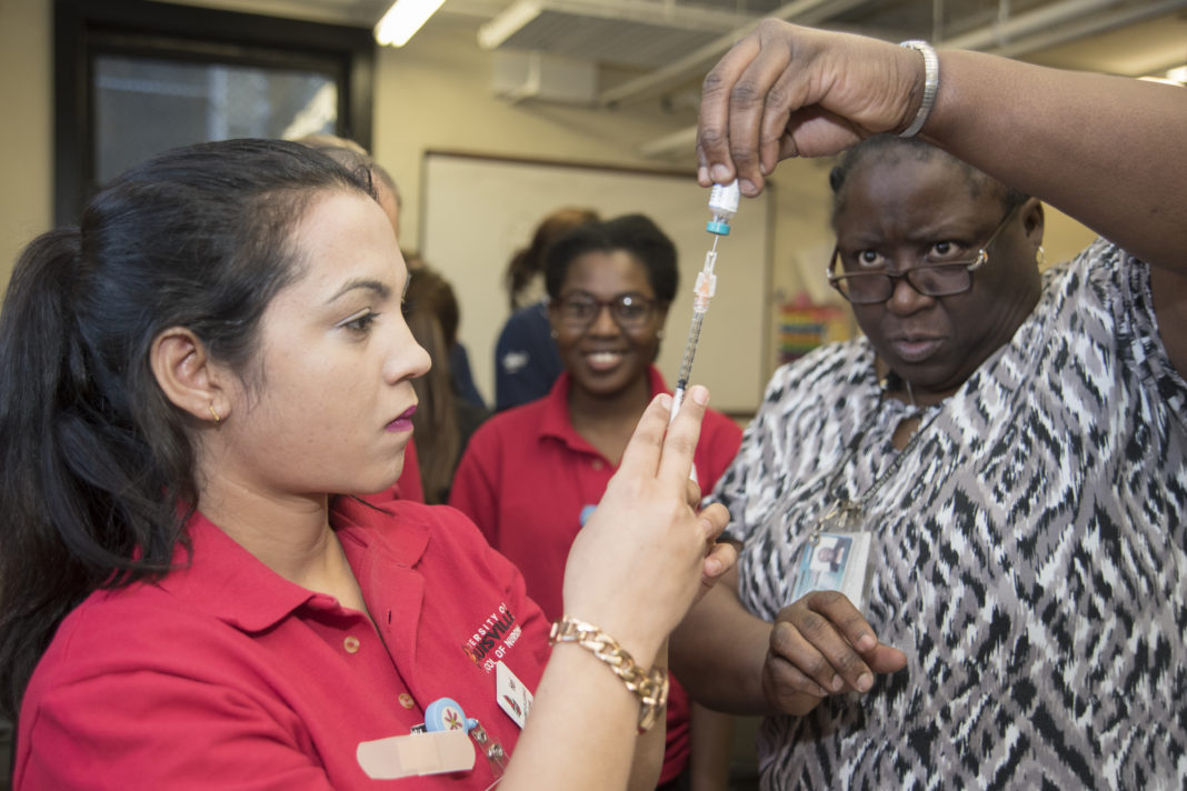 School of Nursing Assistant Professor Montray Smith, right, helps nursing student Hari Poudel prepare a measles, mumps and rubella vaccine at the Kentucky Refugee Ministries on March 14, 2017.