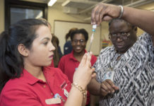 School of Nursing Assistant Professor Montray Smith, right, helps nursing student Hari Poudel prepare a measles, mumps and rubella vaccine at the Kentucky Refugee Ministries on March 14, 2017.