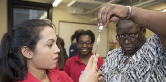 School of Nursing Assistant Professor Montray Smith, right, helps nursing student Hari Poudel prepare a measles, mumps and rubella vaccine at the Kentucky Refugee Ministries on March 14, 2017.