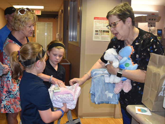 Pauline Hayes, right, NICU manager, accepts blankets and stuffed animals from Madelyn and Shelby Medley on behalf of the UofL Center for Women & Infants.