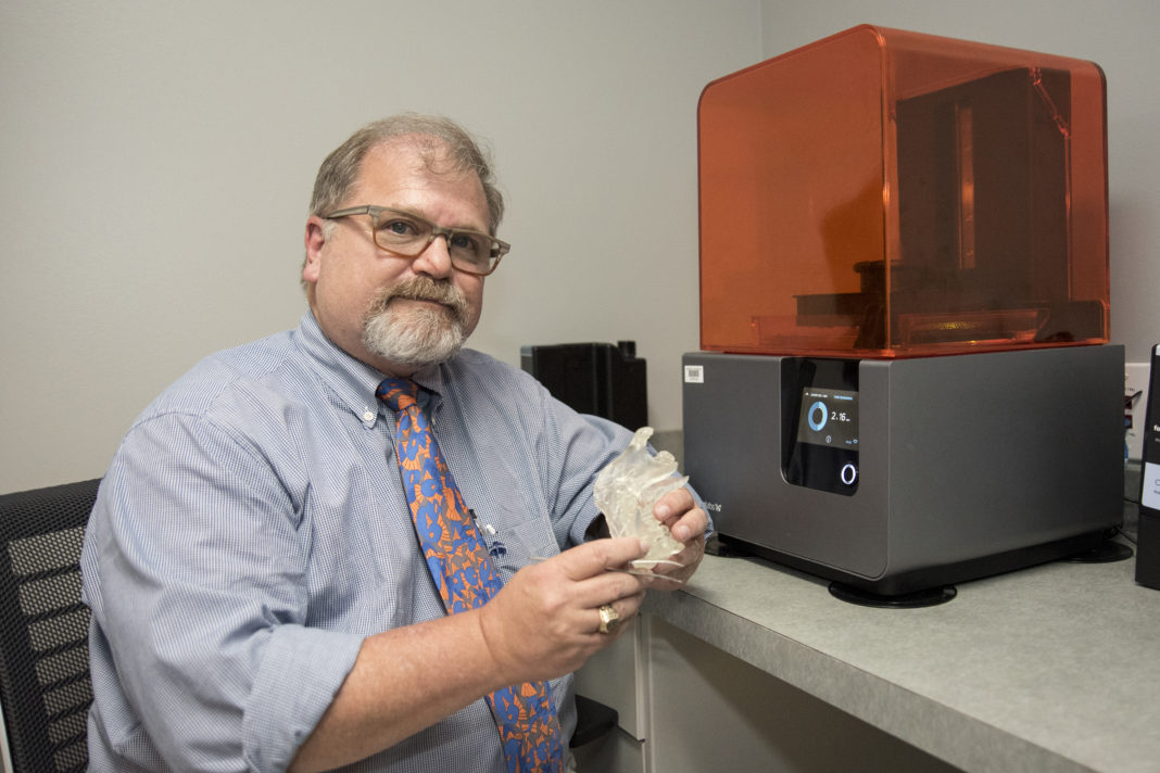 Gerald T. Grant, D.M.D., M.S, holds a 3D model