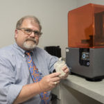 Gerald T. Grant, D.M.D., M.S, holds a 3D model