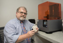 Gerald T. Grant, D.M.D., M.S, holds a 3D model