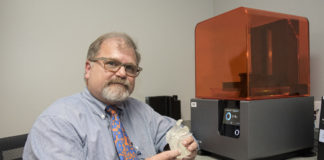 Gerald T. Grant, D.M.D., M.S, holds a 3D model