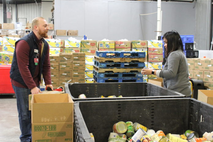 UofL nursing students John Black, left, and Glena Amante pack canned vegetables at Dare to Care Food Bank on March 14, 2018.
