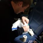 Third-year medical student Matthew Wilson practices a cricothyroidotomy, in which a tube is inserted through the neck to allow a patient to breathe, in an airline seat.