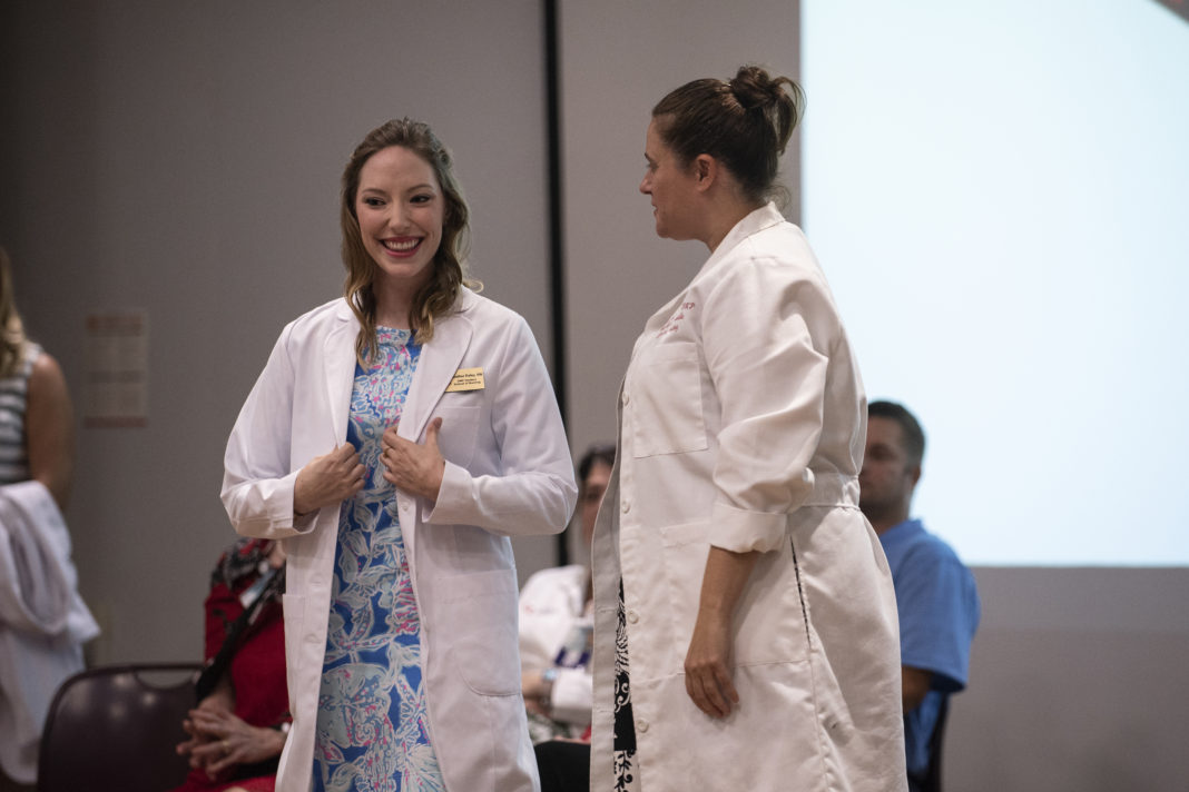 Heather Raley, left, receives her white coat from Sara Robertson, director of the University of Louisville doctor of nursing practice program, during a ceremony on Aug. 16 at the UofL Health Sciences Center.