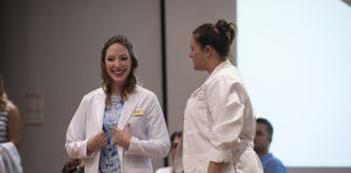Heather Raley, left, receives her white coat from Sara Robertson, director of the University of Louisville doctor of nursing practice program, during a ceremony on Aug. 16 at the UofL Health Sciences Center.