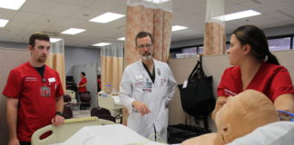 Paul Clark, center, guides UofL School of Nursing students during a clinical simulation.