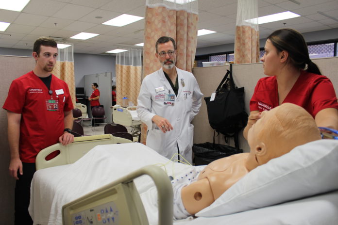Paul Clark, center, guides UofL School of Nursing students during a clinical simulation.
