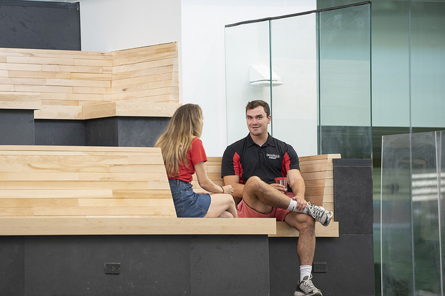 UofL students hang out on the first-floor benches of the Belknap Academic Building. Those benches are made from wood recycled from Crawford Gym, which once stood on the very same site.