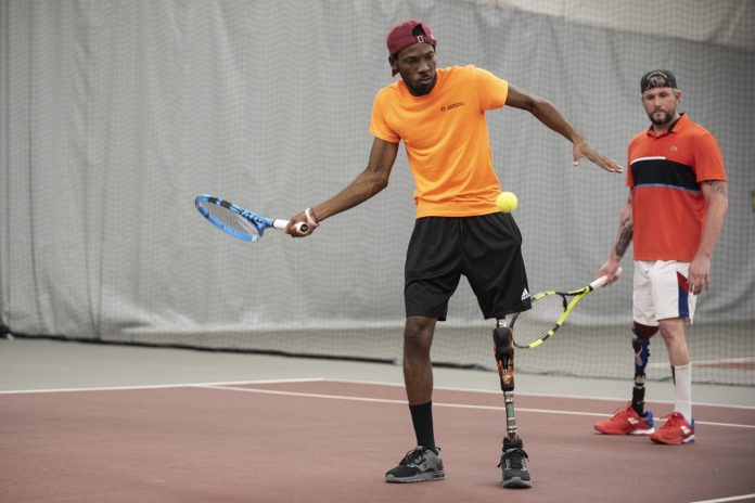 Dionte Foster, left, trains at the UofL Bass-Rudd Tennis Center on his new prosthetic leg.