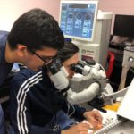 Ophthalmology residents Sidharth Puri, M.D., standing, and Mohammad Ali Sadiq M.D., training in cataract eye surgery using artificial eyes in a ‘wet lab’ at the University of Louisville