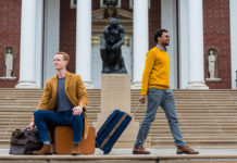 Chris Bird and Kavonte Jones with luggage in front of the Thinker statue on UofL's campus