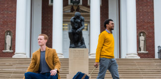 Chris Bird and Kavonte Jones with luggage in front of the Thinker statue on UofL's campus