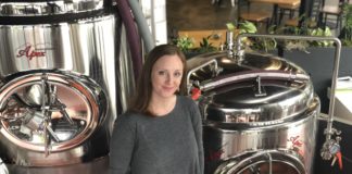 Becky Steele stands in front of equipment at False Idols Brewery.