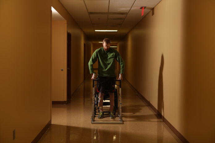 Spinal cord therapy research participant Jeff Marquis stands during therapy. Photo by Jessica Ebelhar.