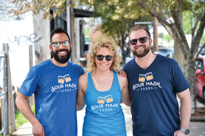 Three people, Dillon Miles, Danielle Huenefeld and Andy Huenefeld, standing together wearing sunglasses during a walking tour of Louisville.