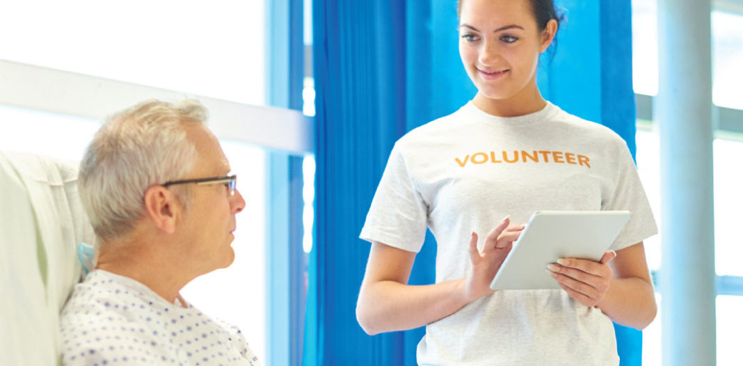 Teen volunteering to help a patient in a health care setting.