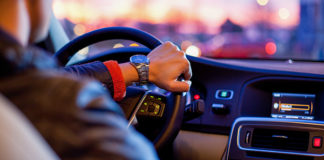 Person driving with one hand on steering wheel