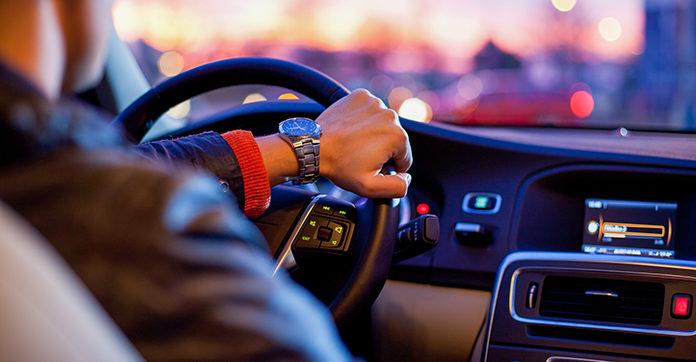 Person driving with one hand on steering wheel