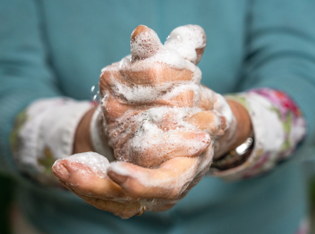 Close-up of an elderly woman's hands as she carefully washes them with soap.