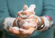 Close-up of an elderly woman's hands as she carefully washes them with soap.