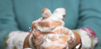 Close-up of an elderly woman's hands as she carefully washes them with soap.