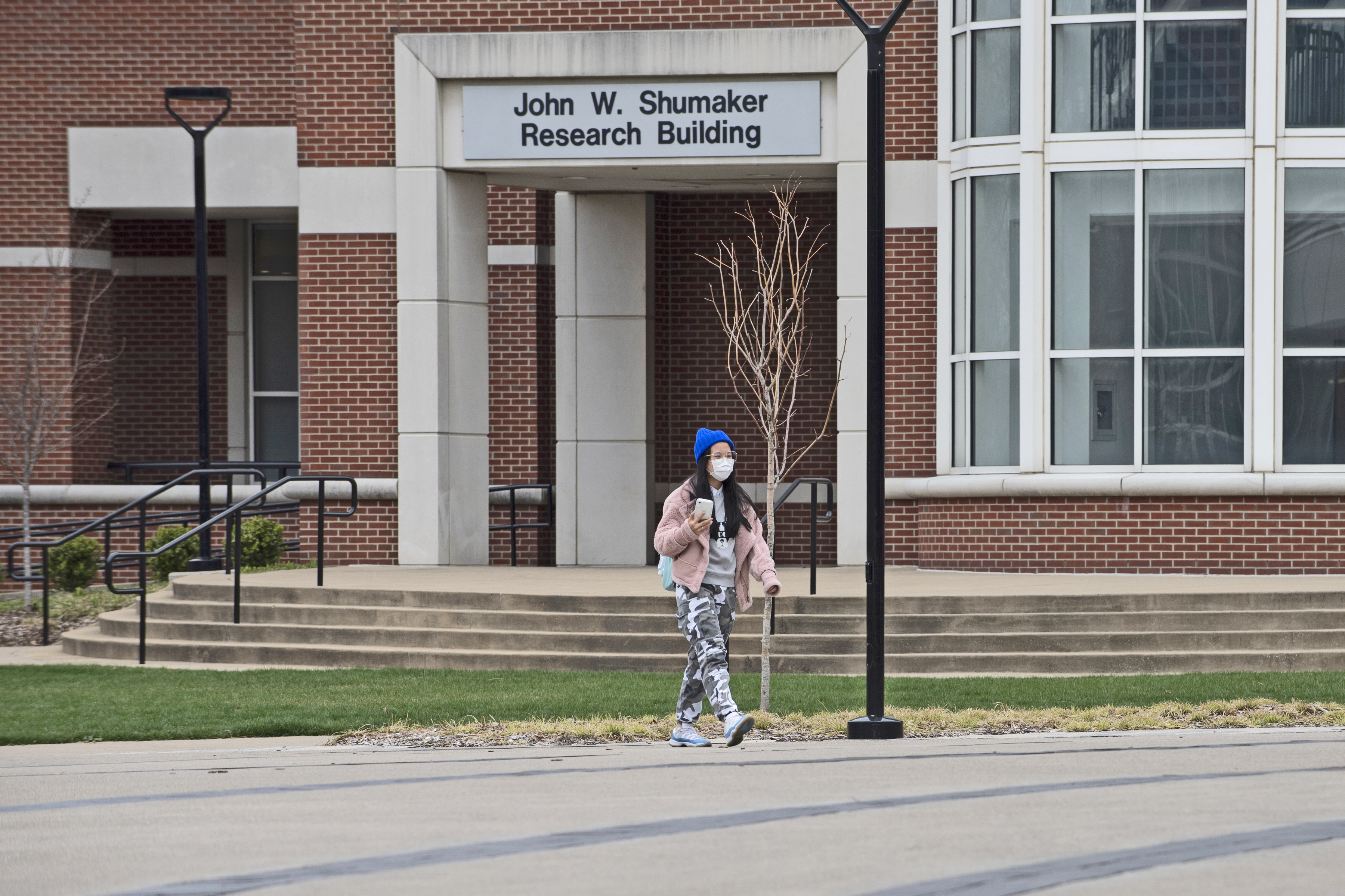 A masked student walks across campus in March, shortly after the COVID-19 pandemic outbreak.
