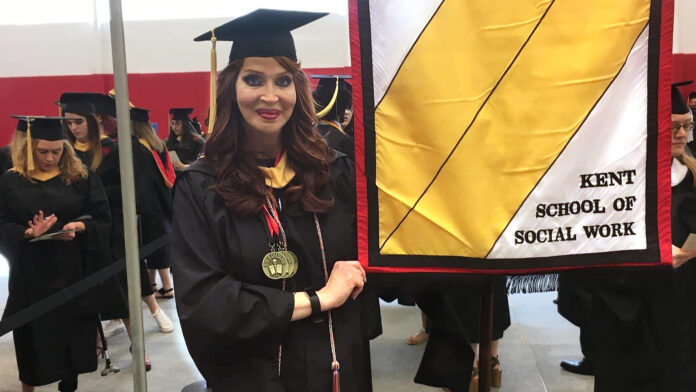 Amirage Saling carrying as the commencement banner bearer for the Kent School of Social Work.