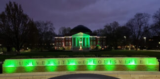 Picture of the university oval entrance and Grawemeyer Hall lit up at night in green to honor COVID-19 victims.