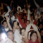 Photo of a group of Black Greek students holding up signs and hand gestures.